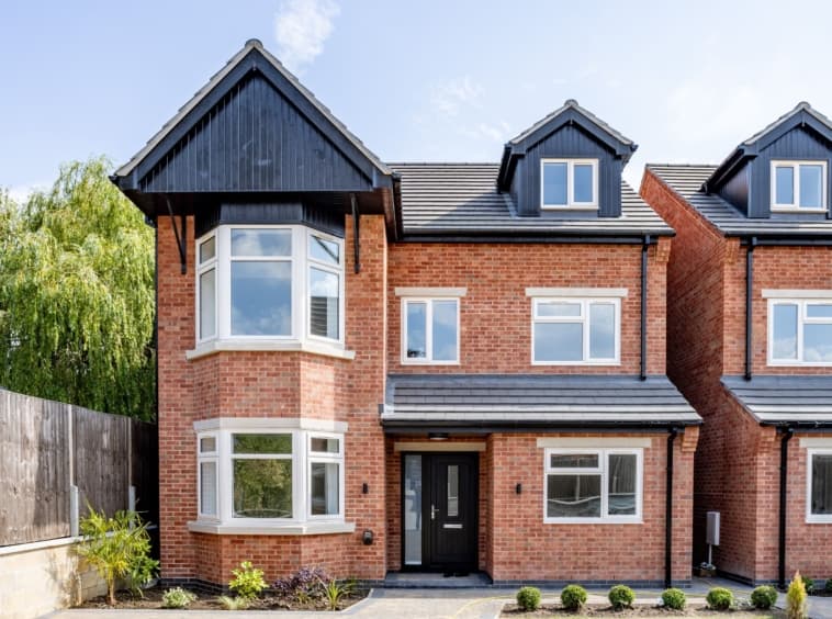 A pair of completed new-build family homes with bay windows and gabled porches