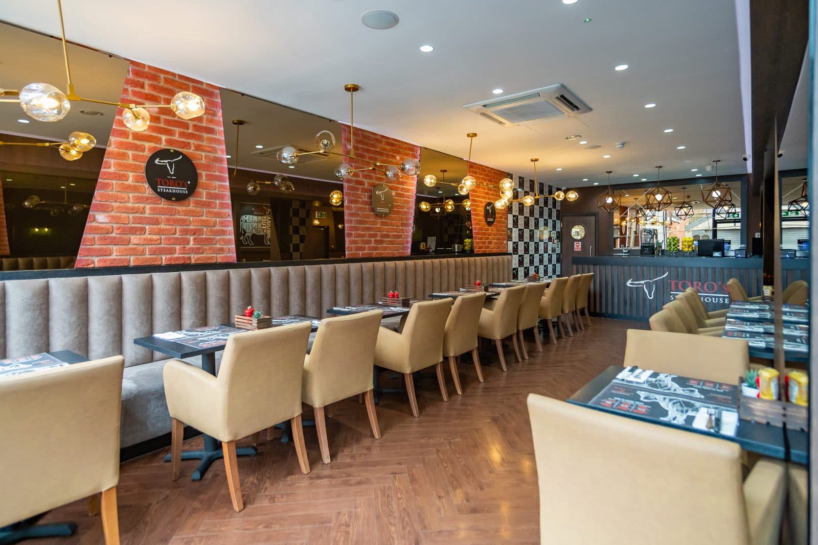Toros Steakhouse dining room with banquette seating, brick piers and pendant lighting