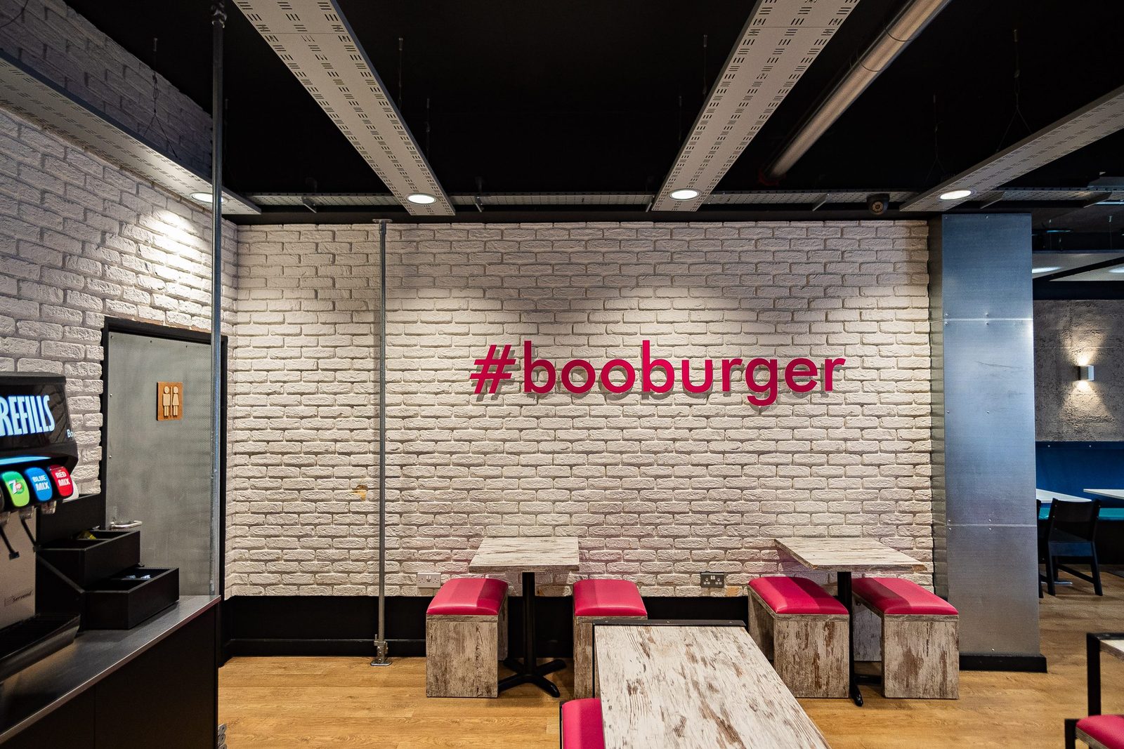 Boo Burger interior with painted brickwork, bench seating and exposed services