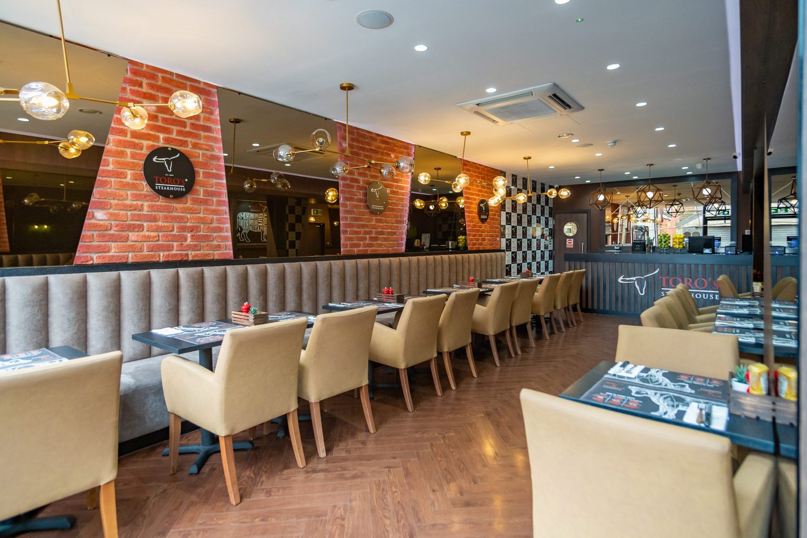 Toros Steakhouse dining room with banquette seating, brick piers and pendant lighting